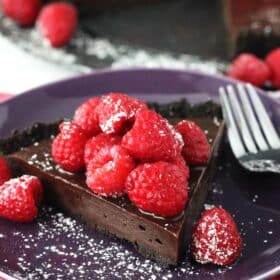 A slice of raspberry nutella tart on a purple plate.