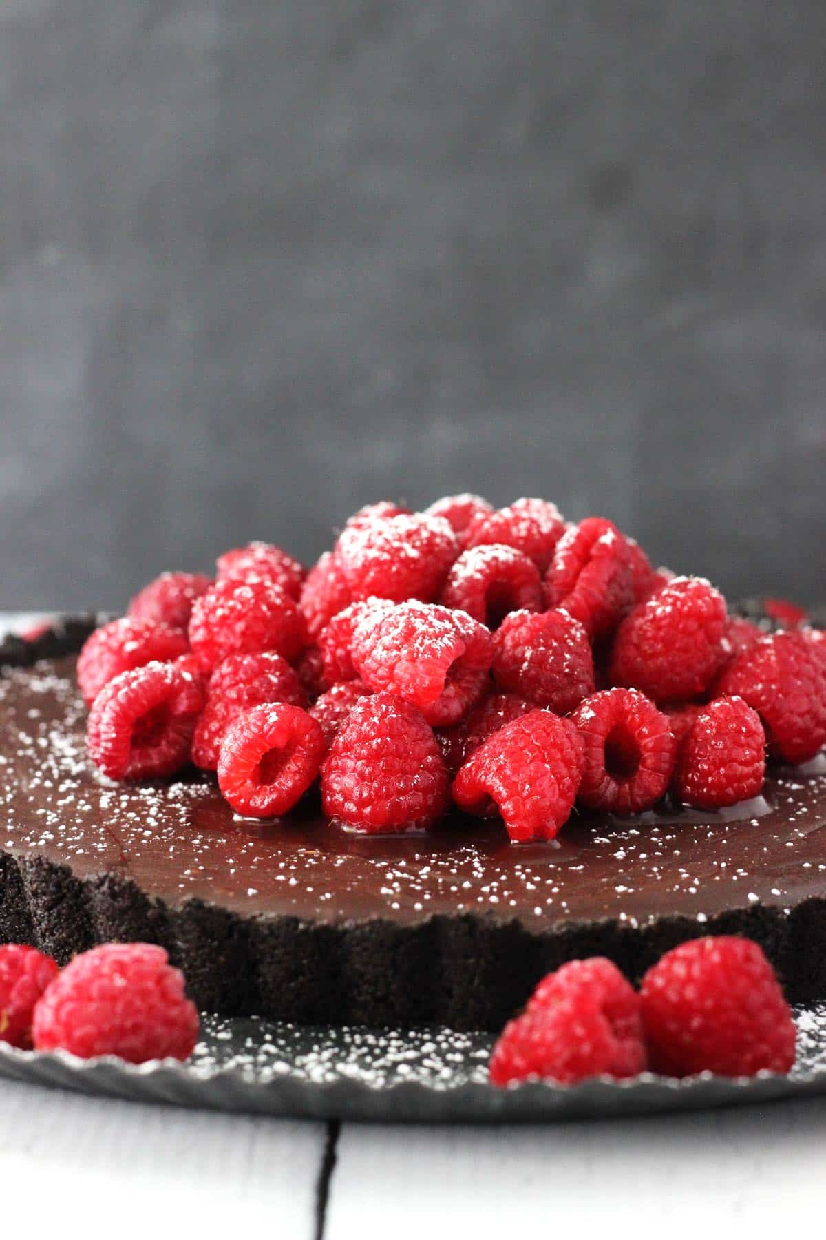 Side view of a raspberry nutella tart sprinkled with powdered sugar.