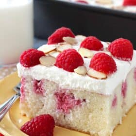 A slice of raspberry almond poke cake on a yellow plate.