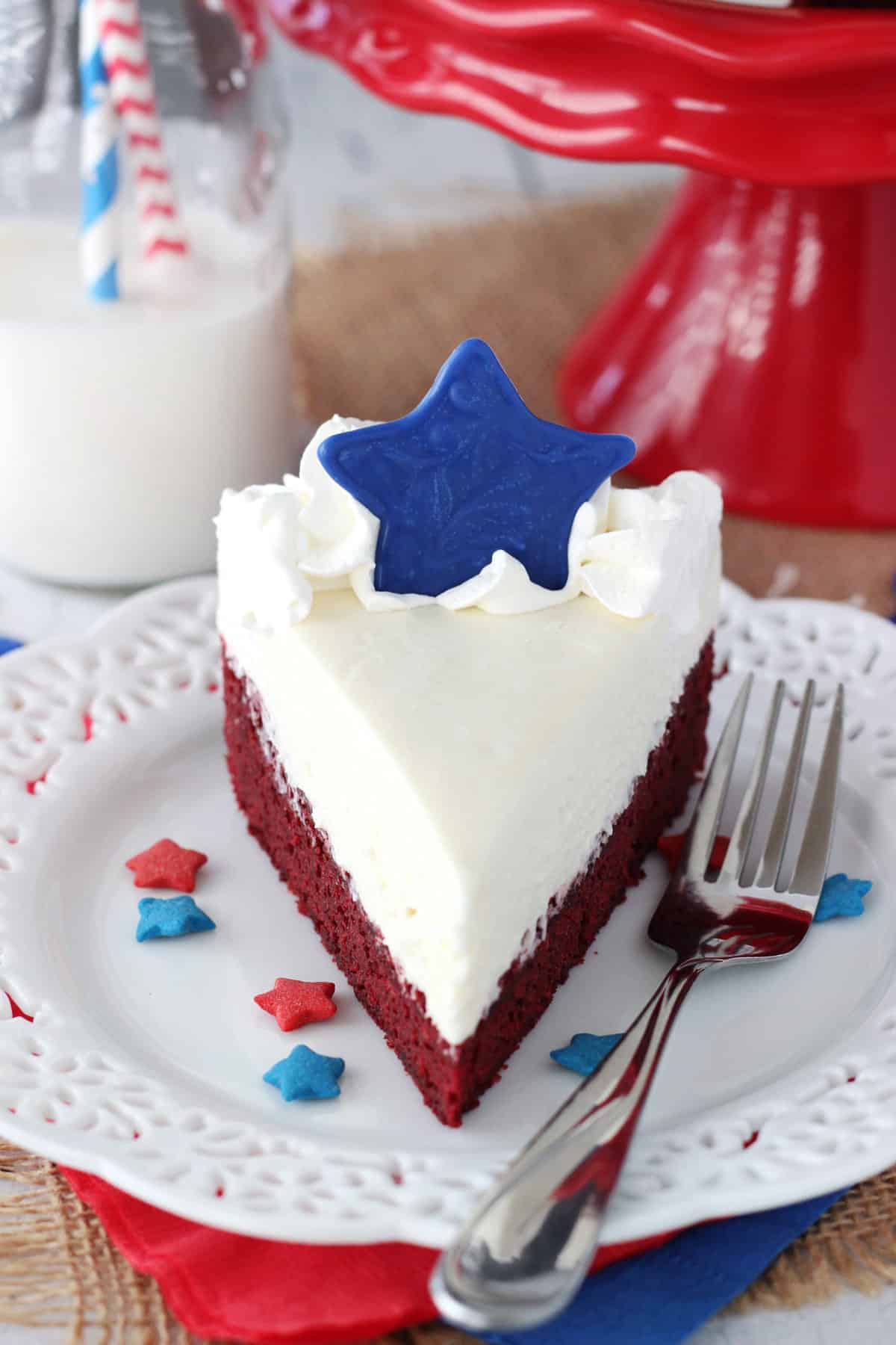 A slice of red velvet blondie cheesecake on a small white plate.