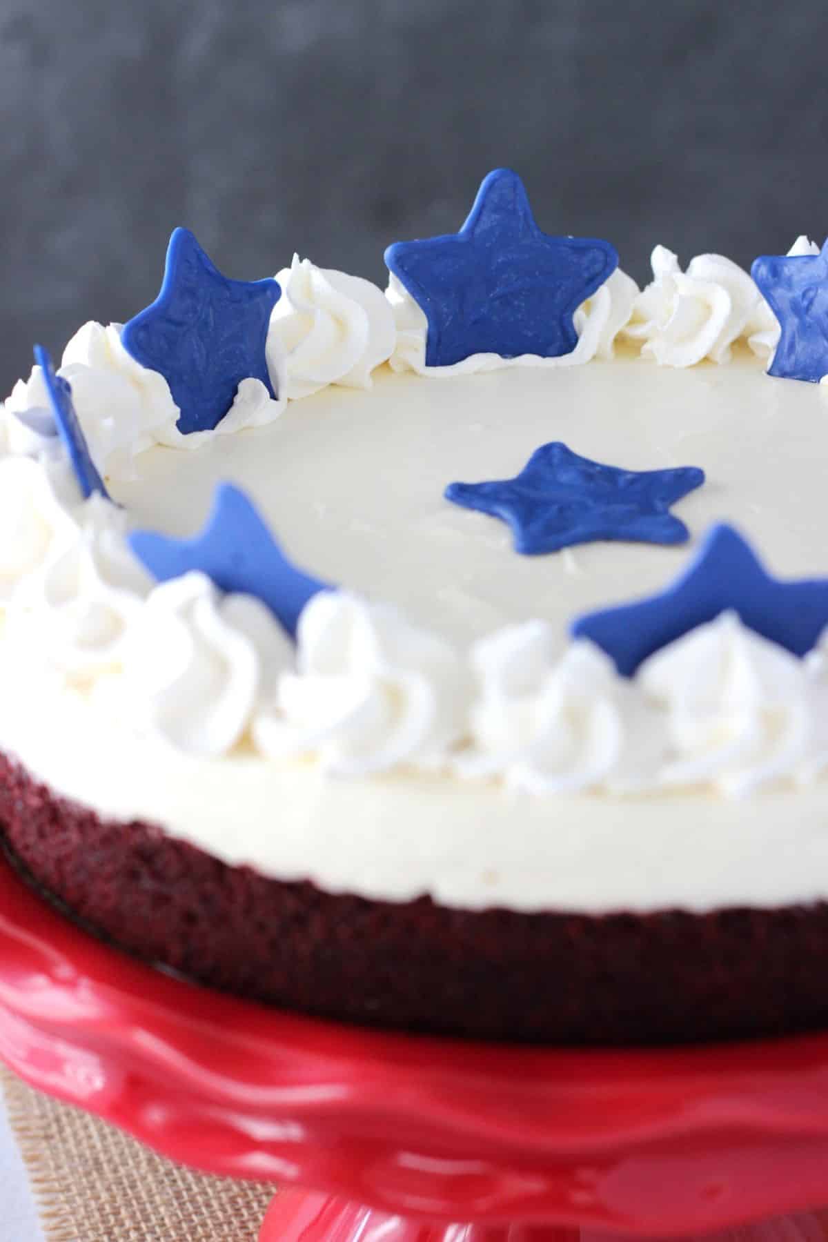 Close up of a red velvet blondie cheesecake on a red cake stand.