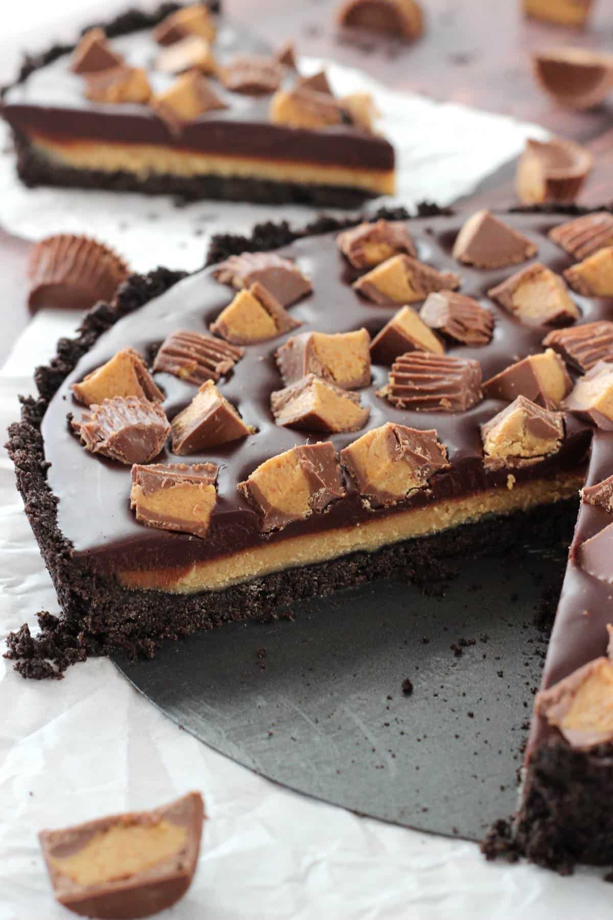 A Reese's chocolate peanut butter tart with a slice missing to show layers.