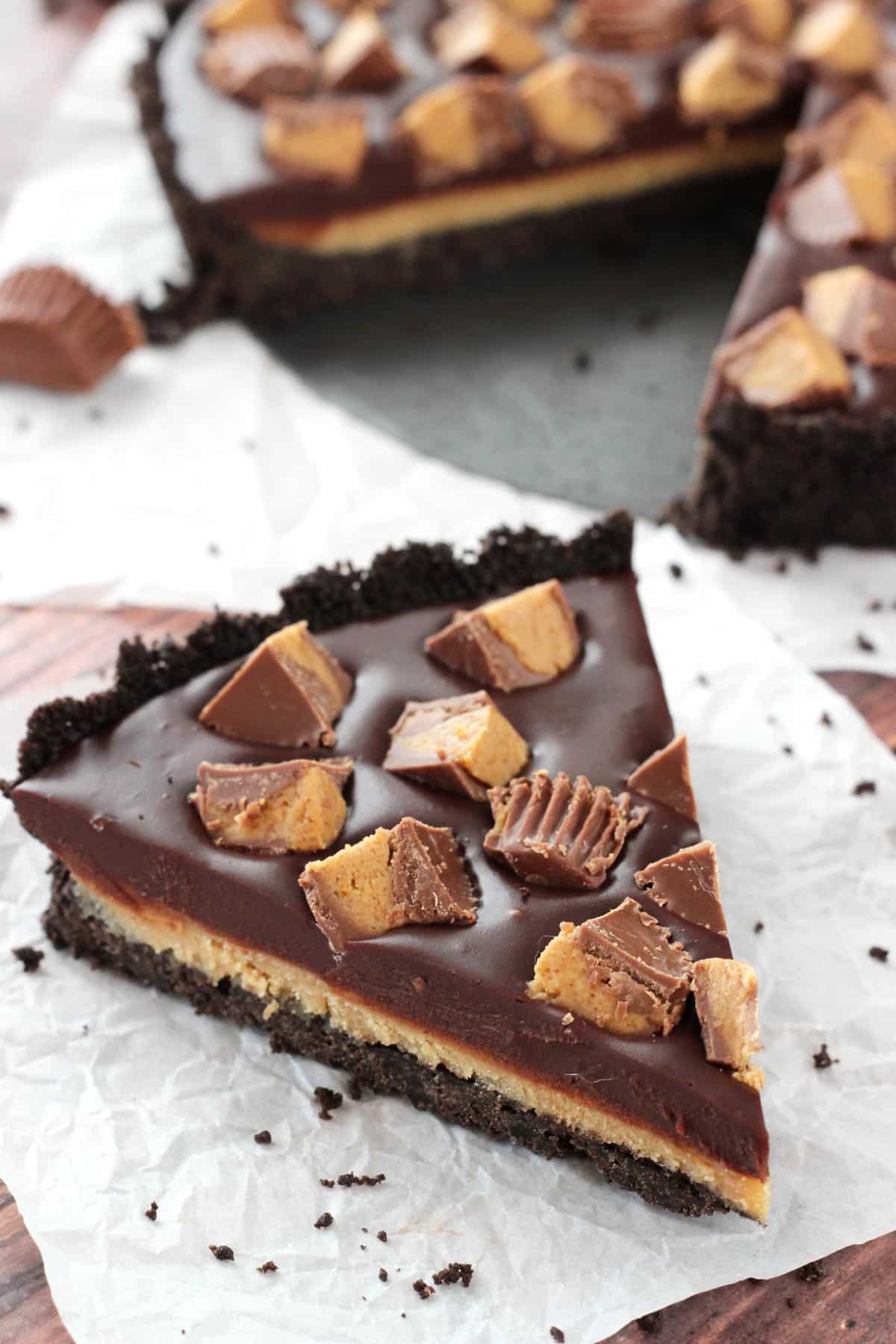 A slice of Reese's chocolate peanut butter tart on a crumpled piece of parchment paper.
