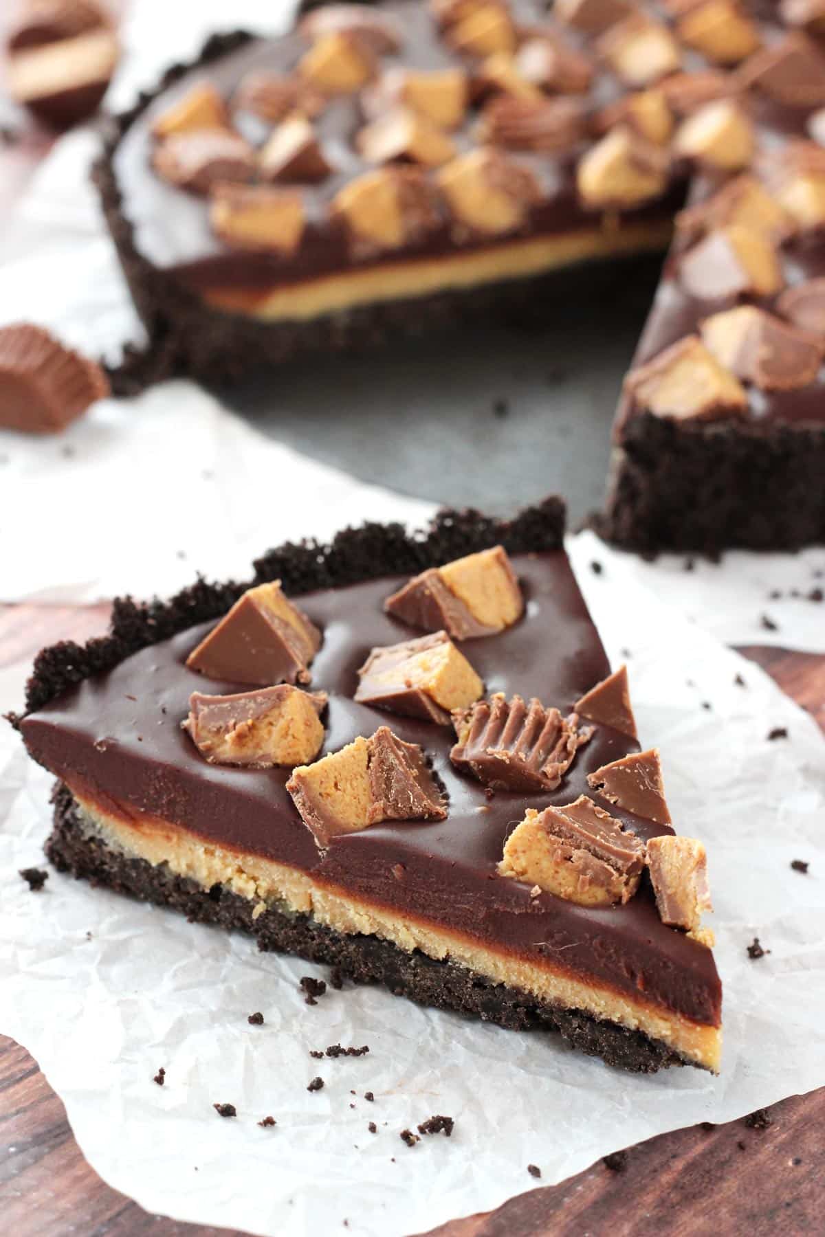 Side view of a slice of Reese's chocolate peanut butter tart on a piece of crumpled parchment paper.