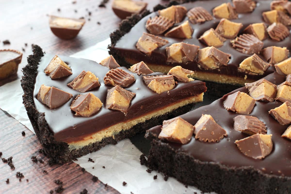 A slice of Reese's chocolate peanut butter tart just barely removed from the rest of the tart.