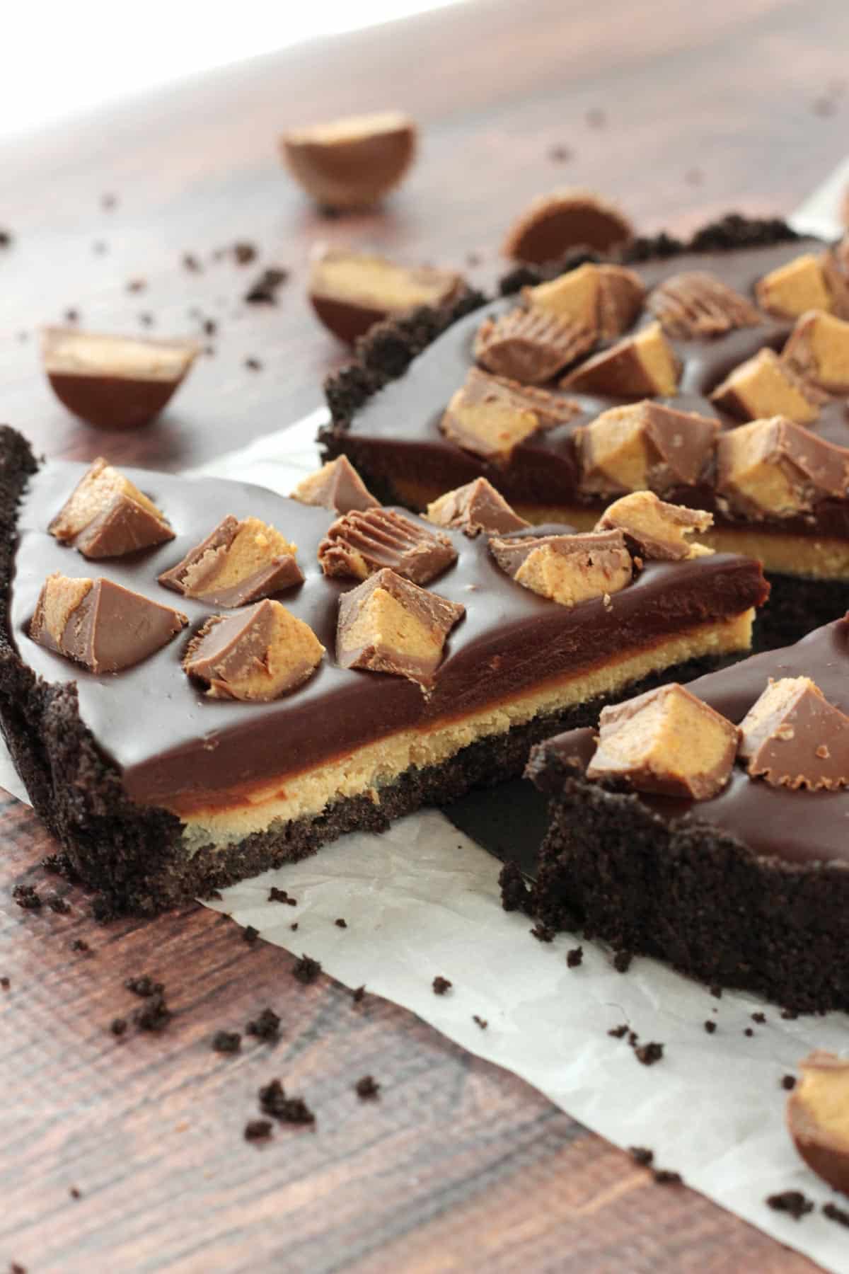 A slice of Reese's chocolate peanut butter tart just barely removed from the rest of the tart.