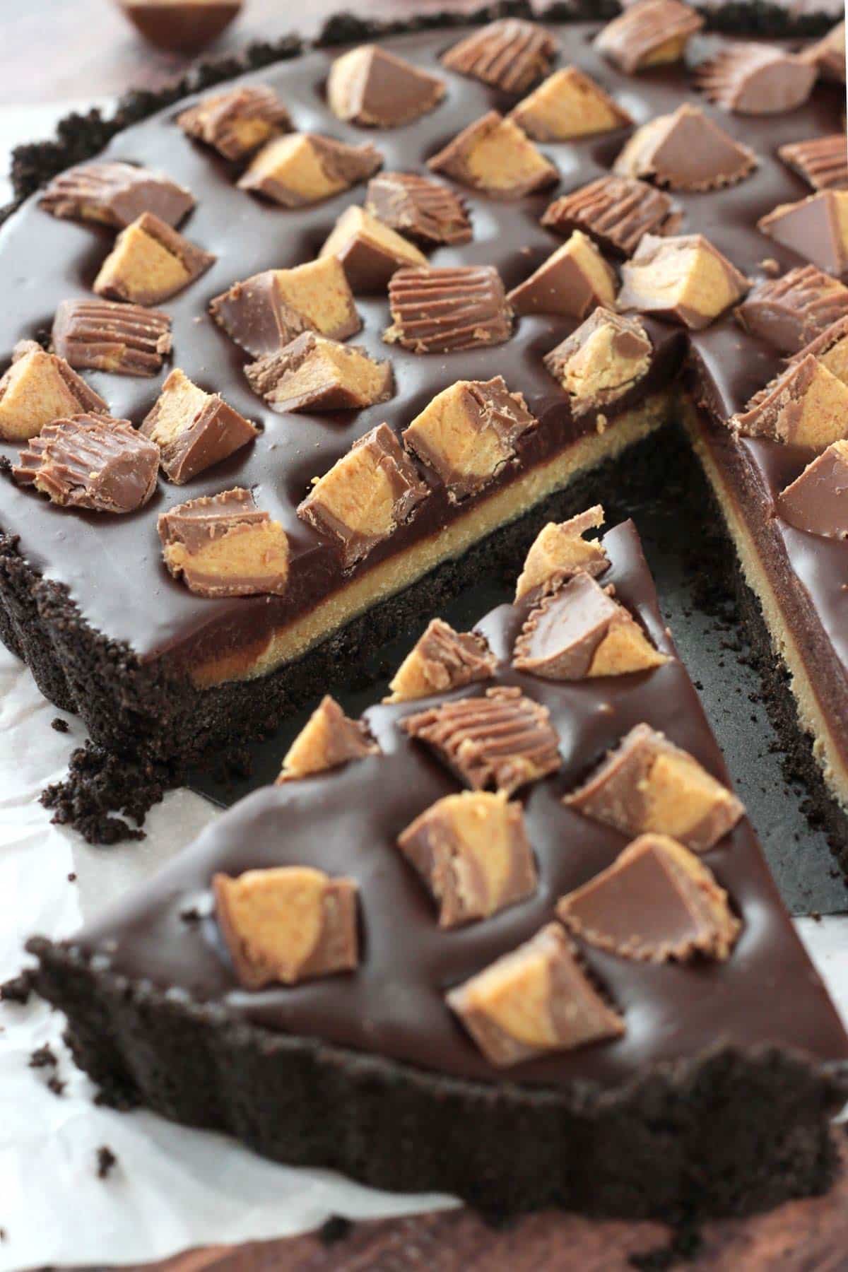 A slice of Reese's chocolate peanut butter tart that's just barely removed from the rest of the tart.