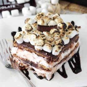 Close up of a slice of smores icebox cake on a white square plate.