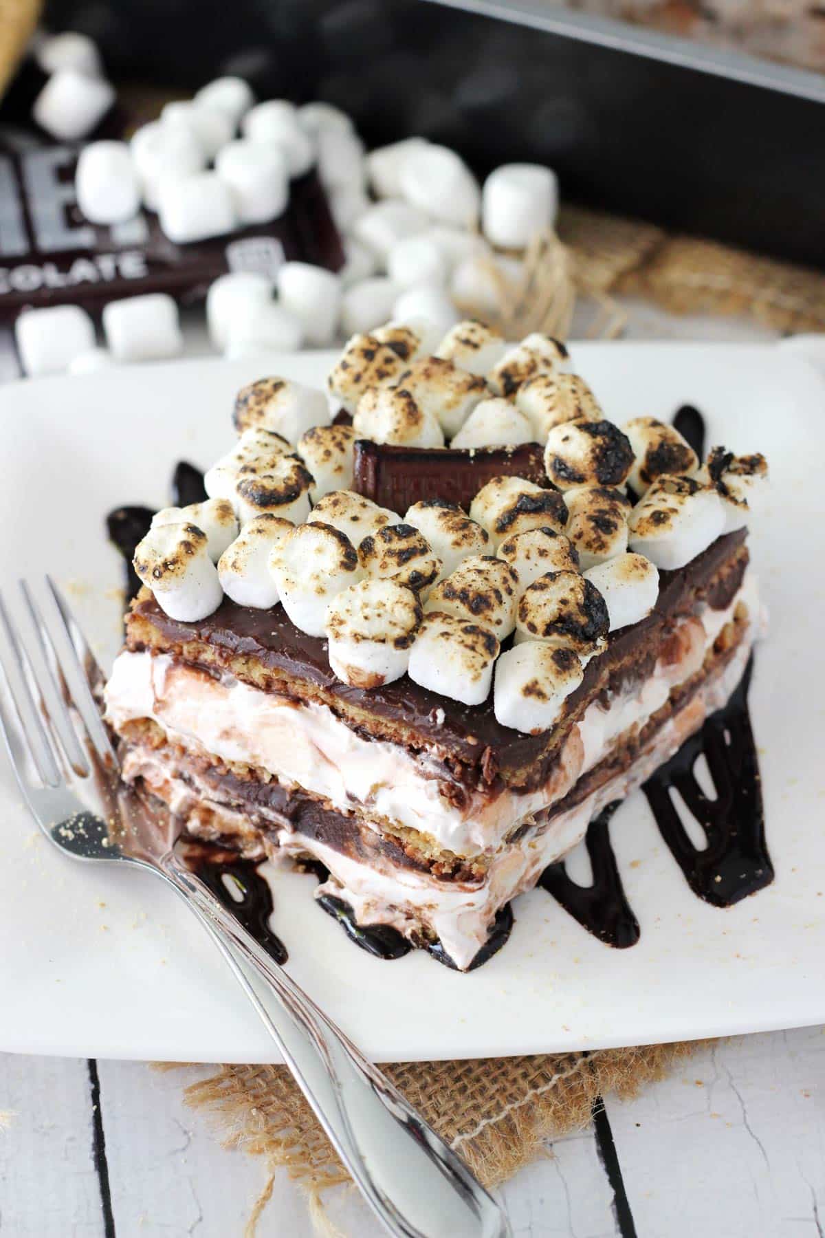Close up of a slice of smores icebox cake on a white square plate.
