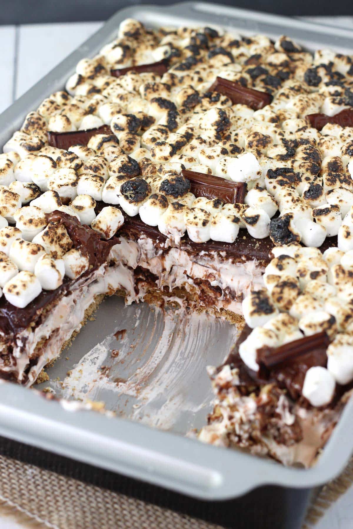A baking pan filled with smores icebox cake with a slice removed.