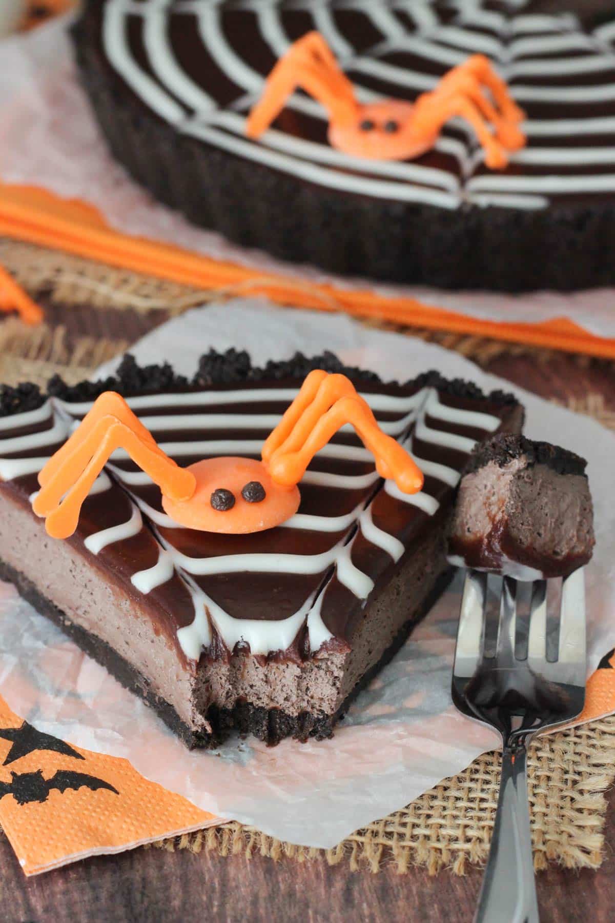 A slice of spiderweb chocolate tart with a bite removed on a fork.
