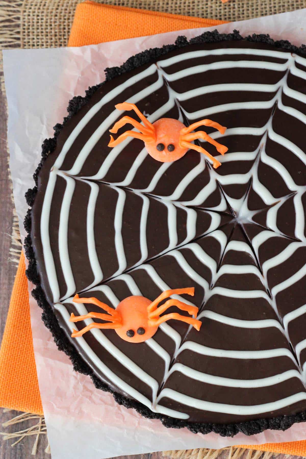 Top view of a spiderweb chocolate tart with two candy spiders on top.