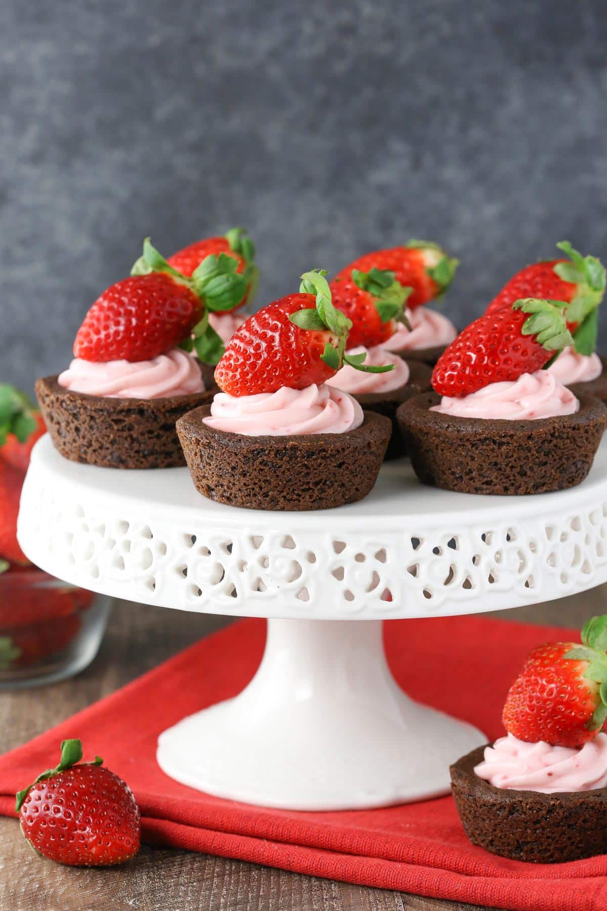 A white cake stand topped with strawberry cheesecake chocolate cookie cups.