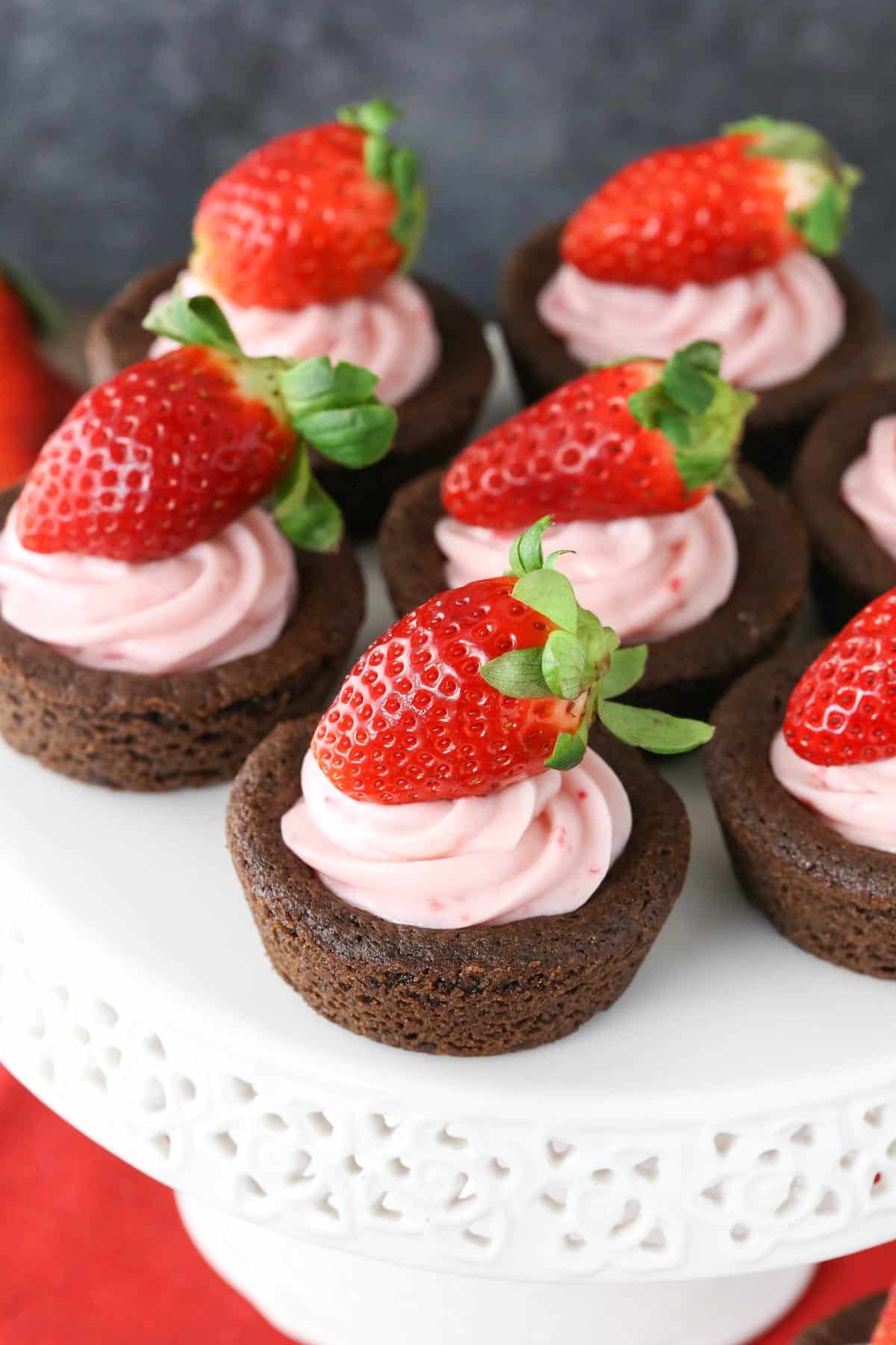 Overhead view of strawberry cheesecake chocolate cookie cups on a white cake stand.