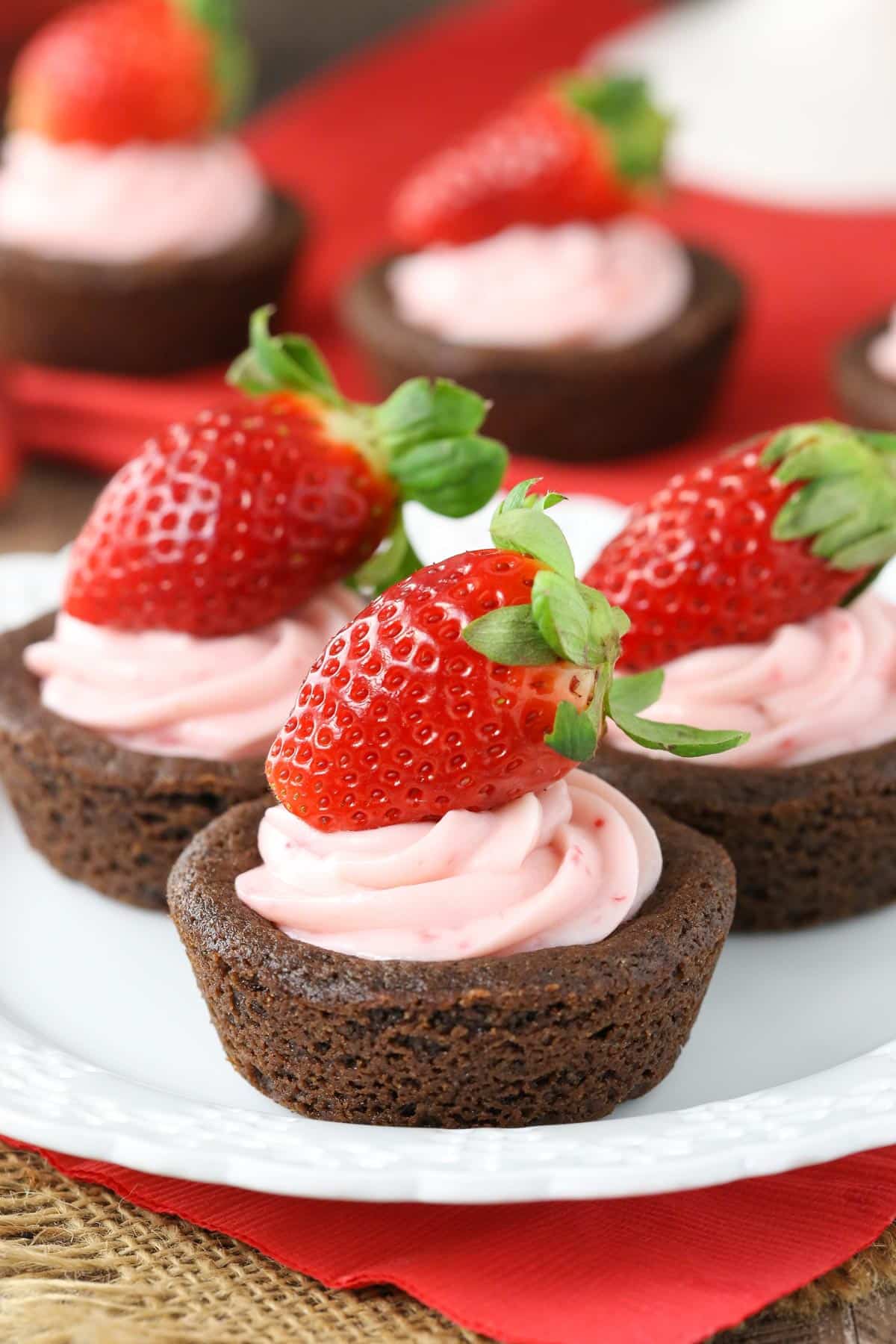 Close up of strawberry cheesecake chocolate cookie cups on a white plate.