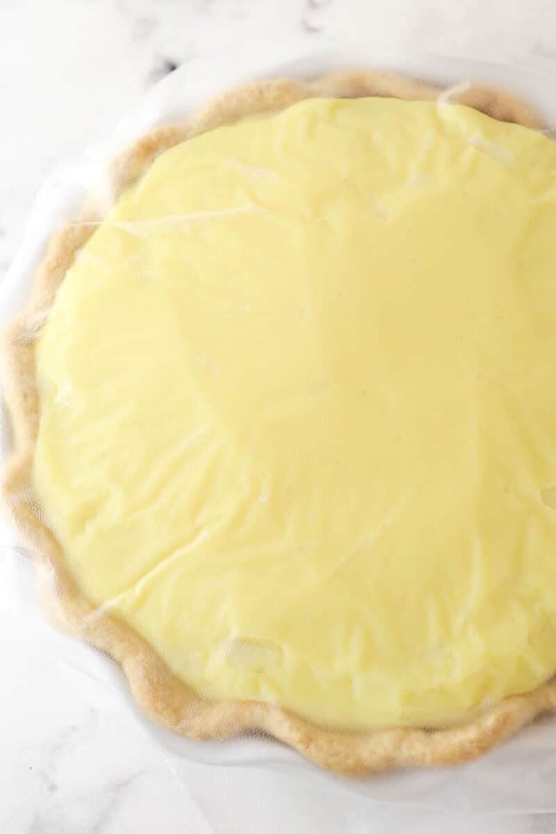 Banana pudding pie covered with plastic wrap