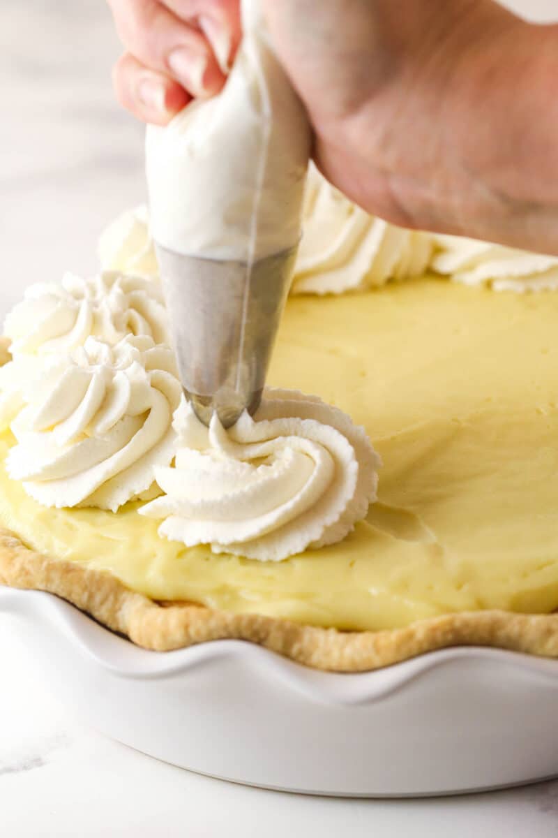 Piping whipped cream onto banana pudding pie