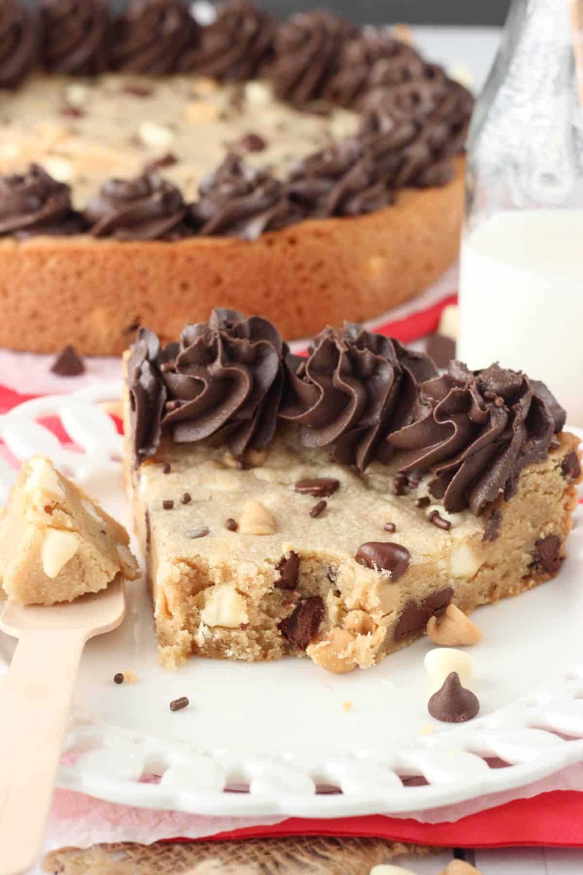 A slice of triple chocolate chip cookie cake with a few bites removed on a white plate.