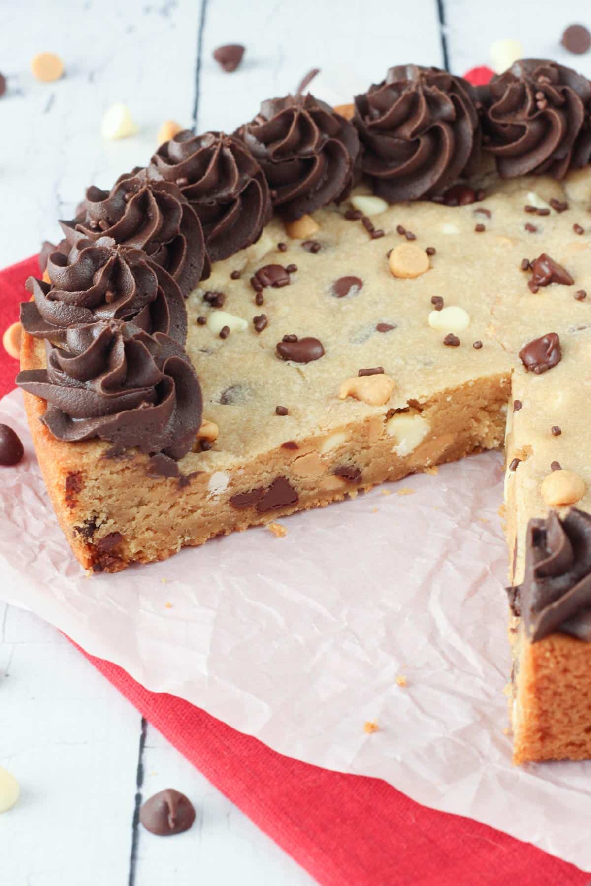 A triple chocolate chip cookie cake with a slice removed to show inside.