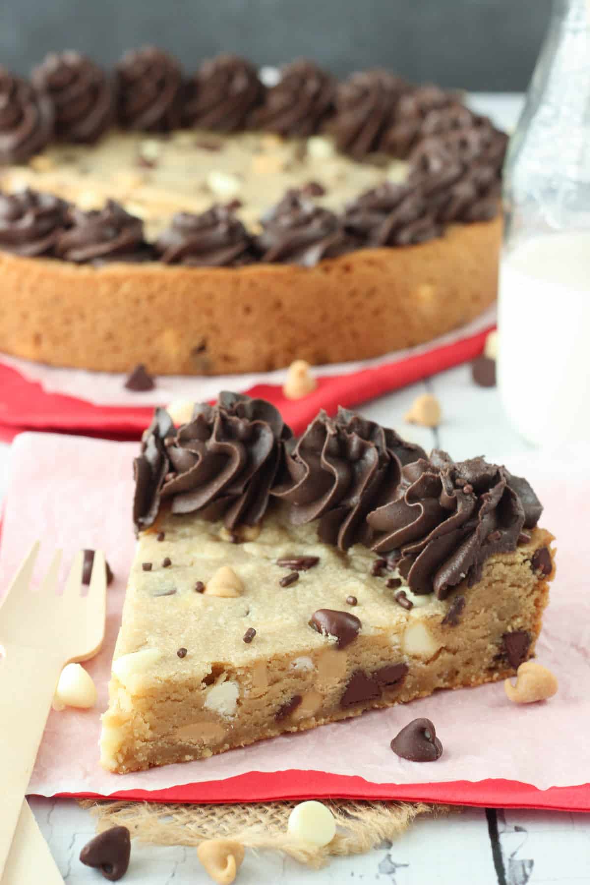 A slice of triple chocolate chip cookie cake with the rest of the cake in the background.
