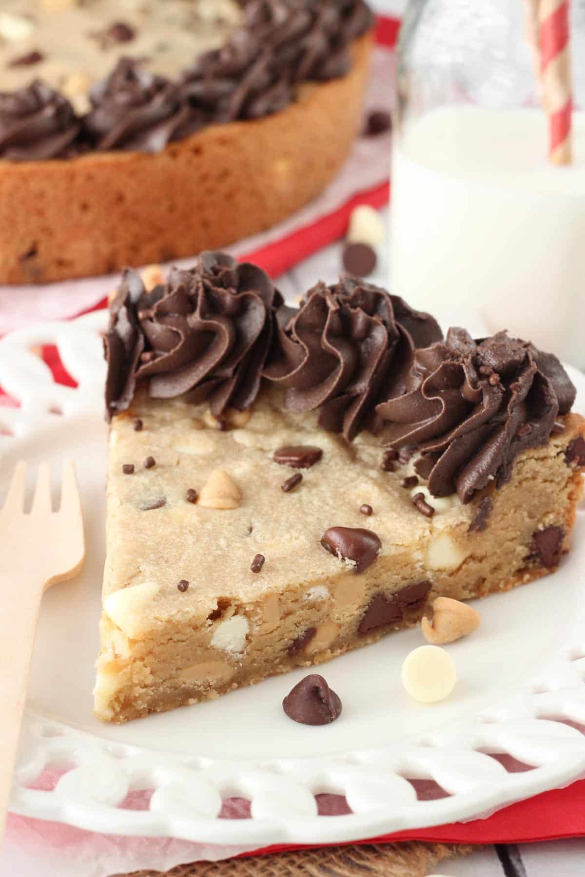 Side view of a slice of triple chocolate chip cookie cake on a white plate.