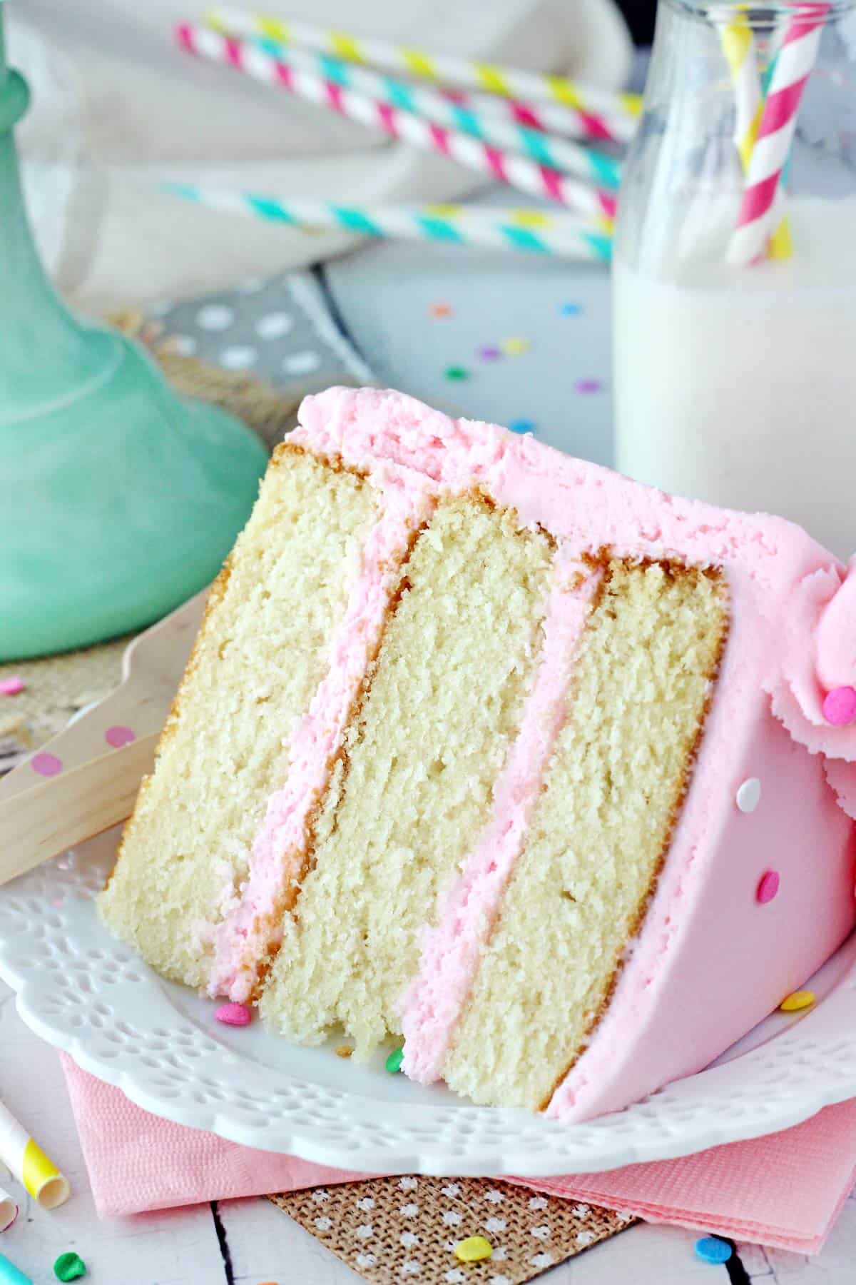 Close up of a slice of vanilla cake on a white plate.