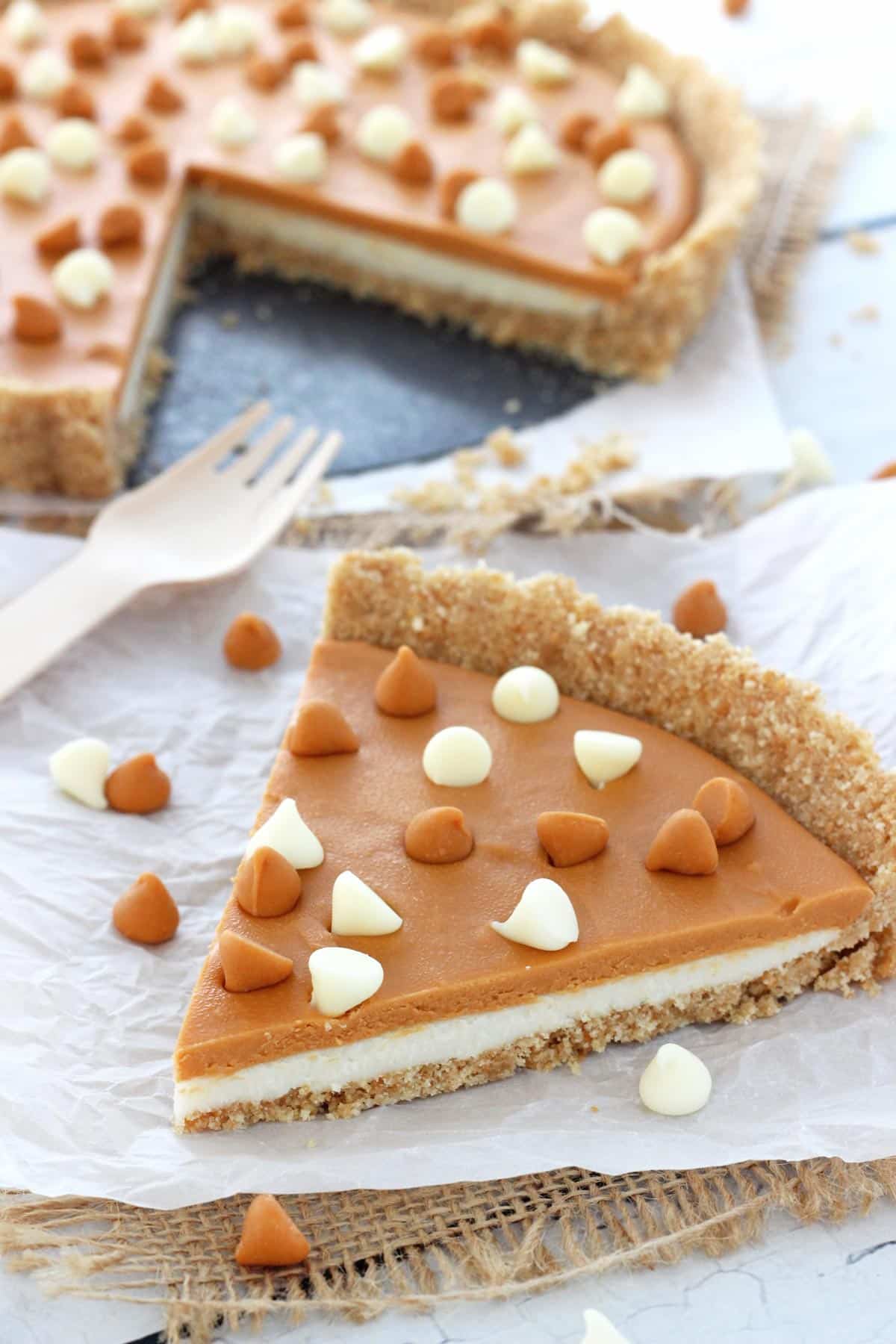 Close up of a slice of white chocolate butterscotch tart with the rest of the tart in the background.
