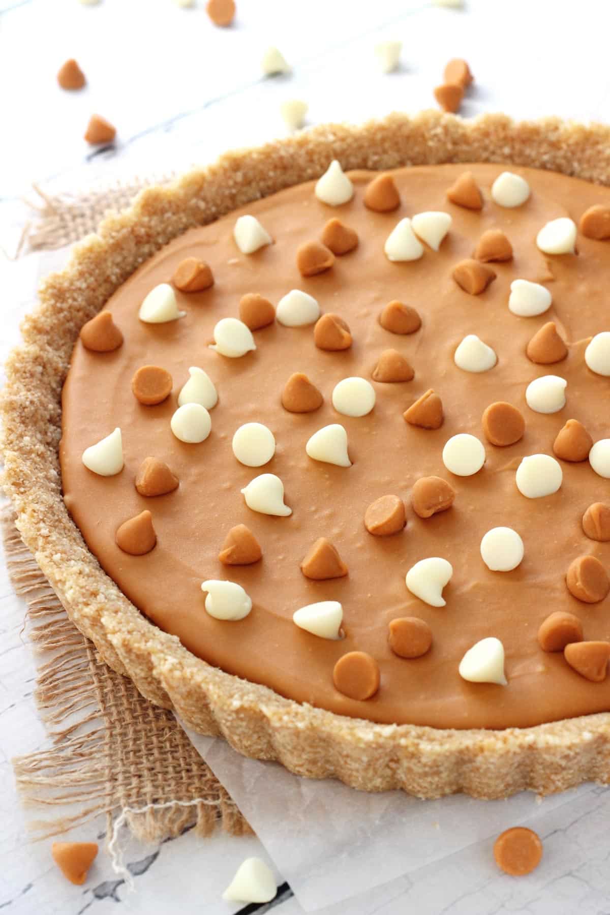 Close up of half of a white chocolate butterscotch tart on a piece of burlap.