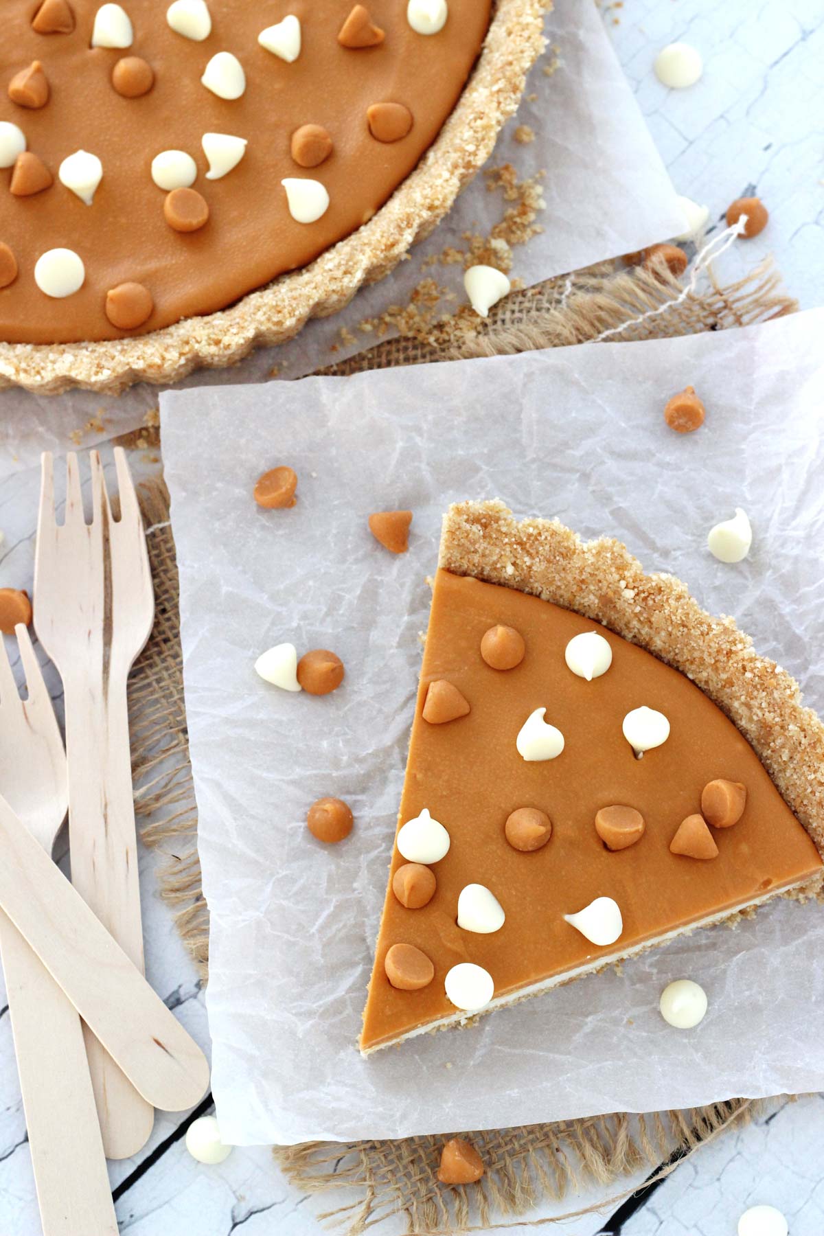 Overhead view of a slice of white chocolate butterscotch tart on a piece of parchment paper.