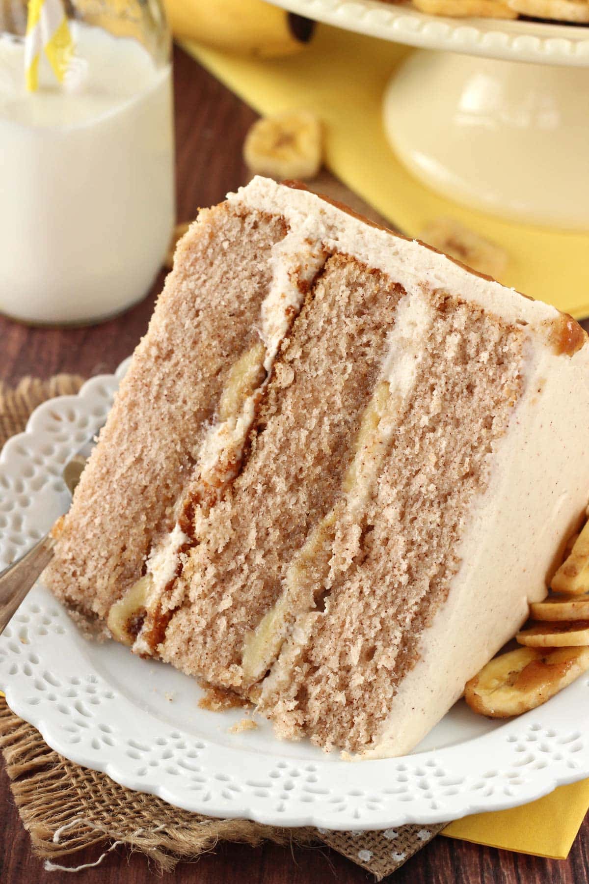 Close up of a slice of bananas foster layer cake on a small white plate.