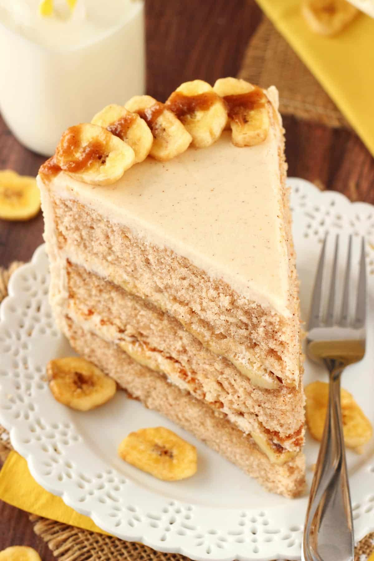 Overhead view of a slice of bananas foster layer cake on a small white plate.