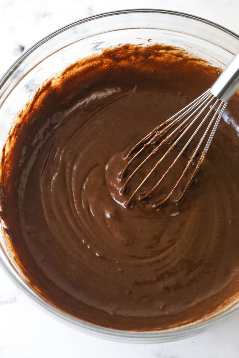 These Black Bottom Cupcakes combine two desserts in one with a rich chocolate cupcake and a creamy chocolate chip cheesecake filling. Chocolate cupcake batter in a bowl with a whisk