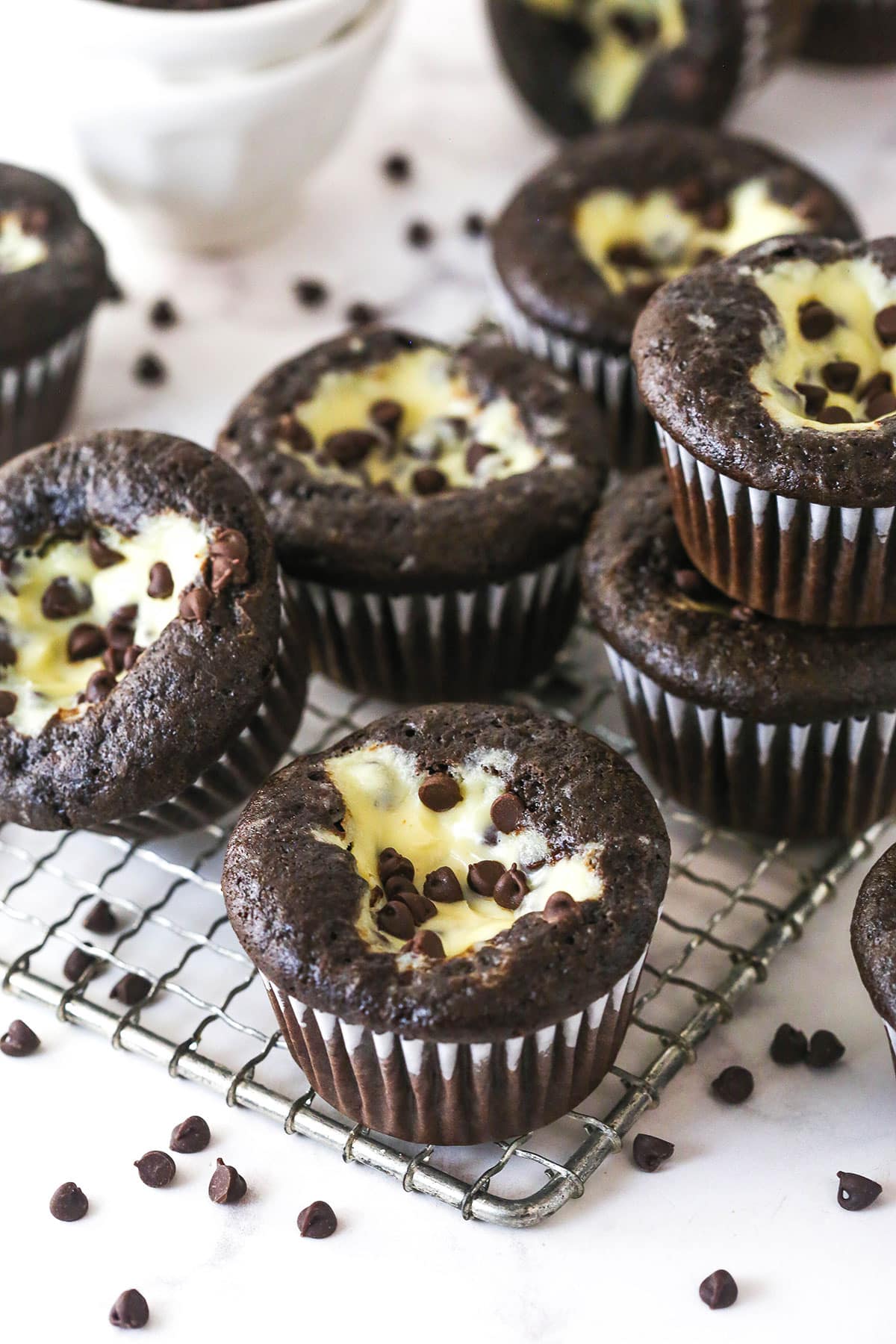 These Black Bottom Cupcakes combine two desserts in one with a rich chocolate cupcake and a creamy chocolate chip cheesecake filling. Black bottom cupcakes stacked on a wire rack
