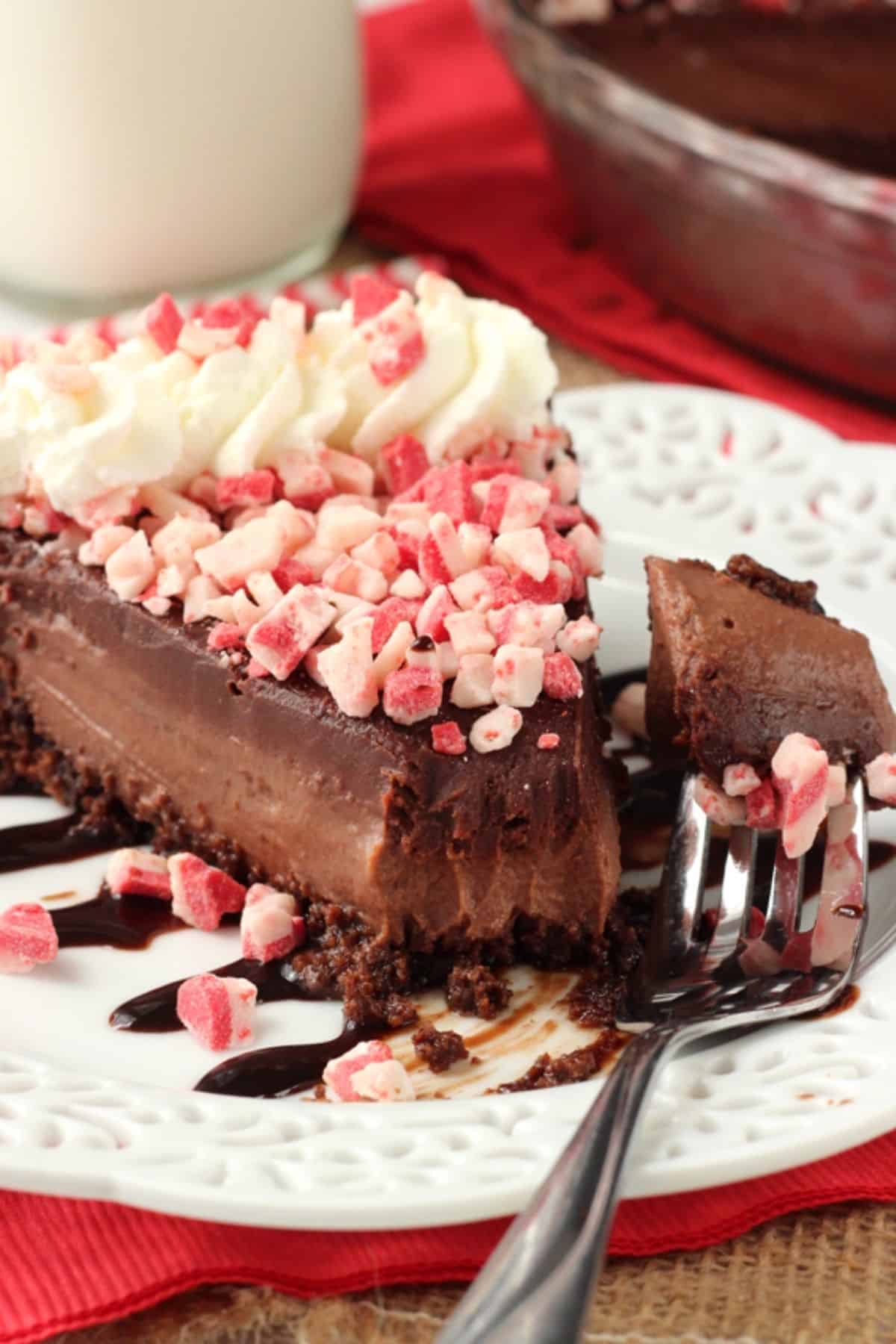 A slice of Brownie Brittle peppermint chocolate pie on a white plate with a bite removed on a fork.