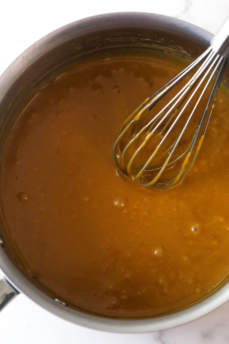 These Caramel Cookie Bars combine gooey caramel and chewy chocolate chip cookies in one perfect dessert. Easy to make! Melting caramel and butter on the stovetop