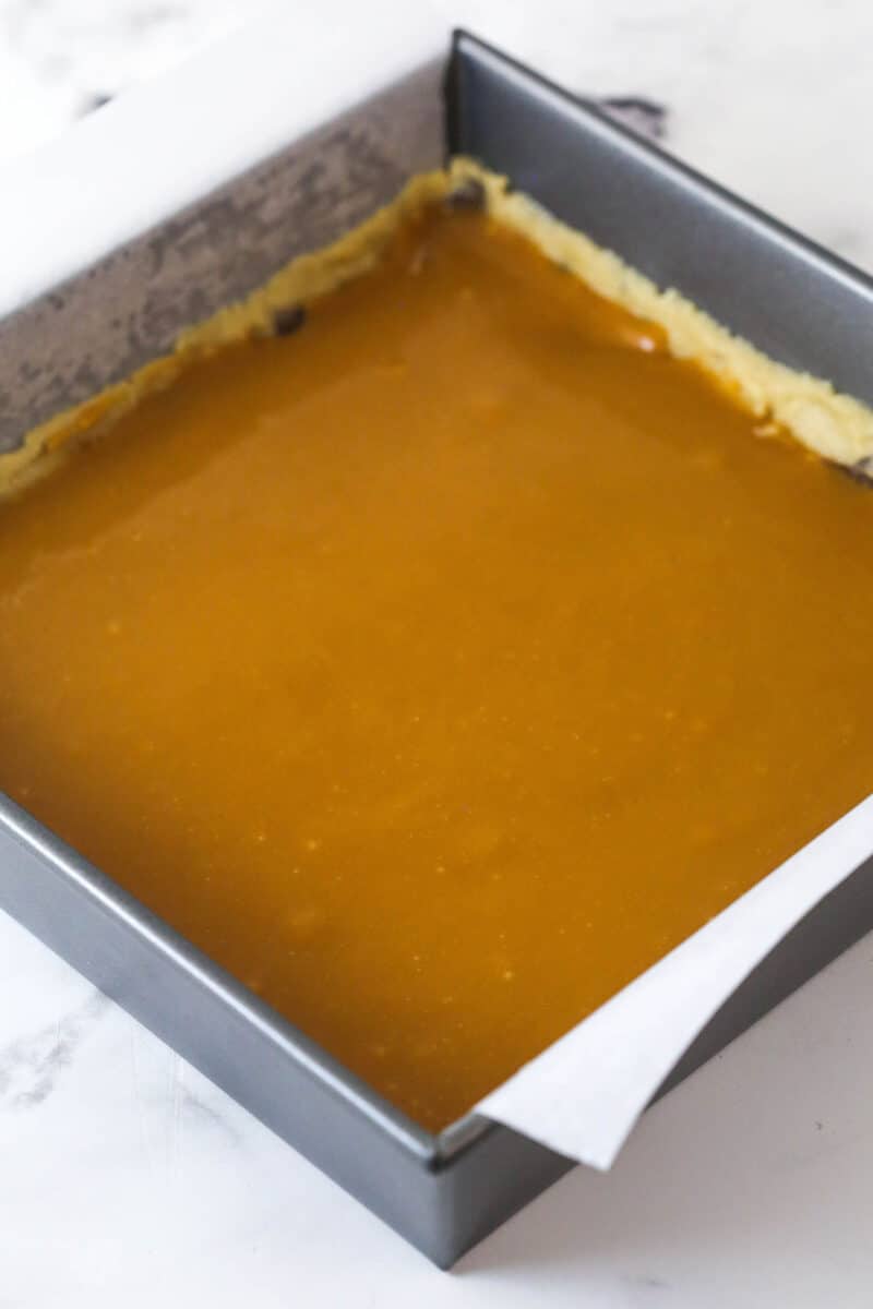 These Caramel Cookie Bars combine gooey caramel and chewy chocolate chip cookies in one perfect dessert. Easy to make! Melted caramel poured over cookie dough in a square pan