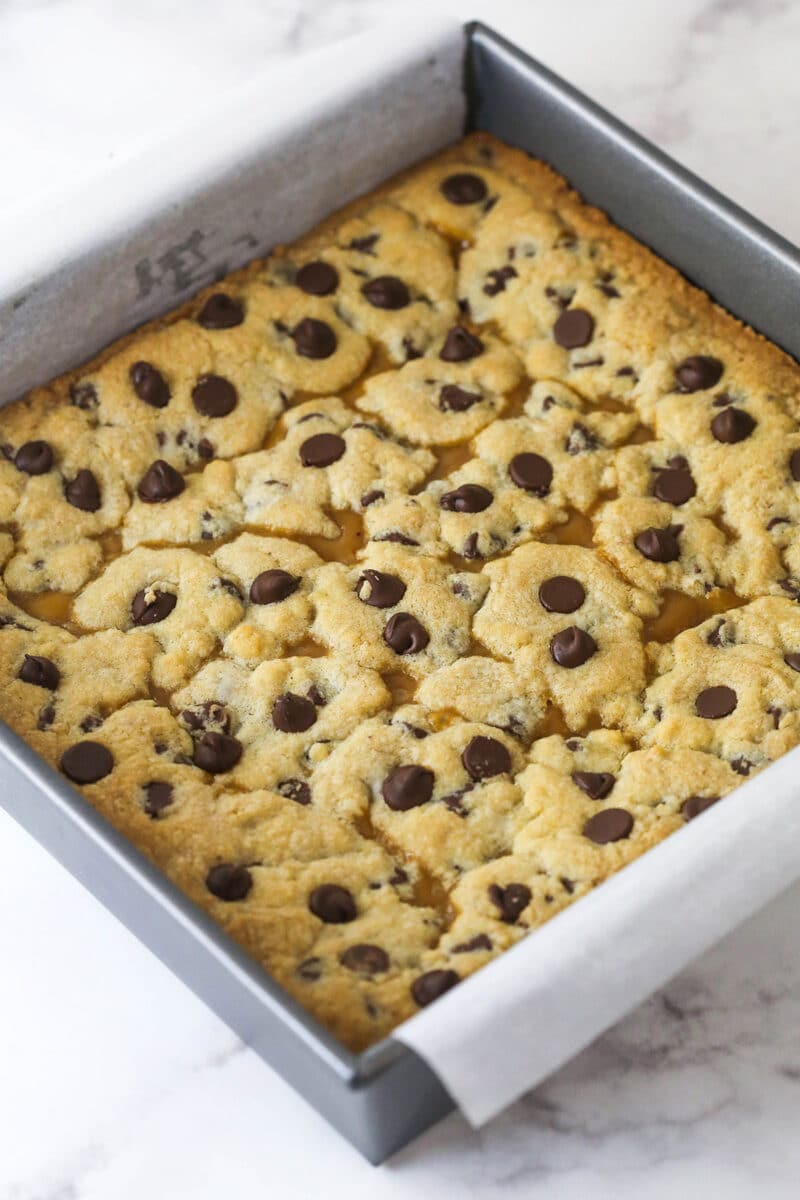 These Caramel Cookie Bars combine gooey caramel and chewy chocolate chip cookies in one perfect dessert. Easy to make! Baked caramel cookie bars in a square pan
