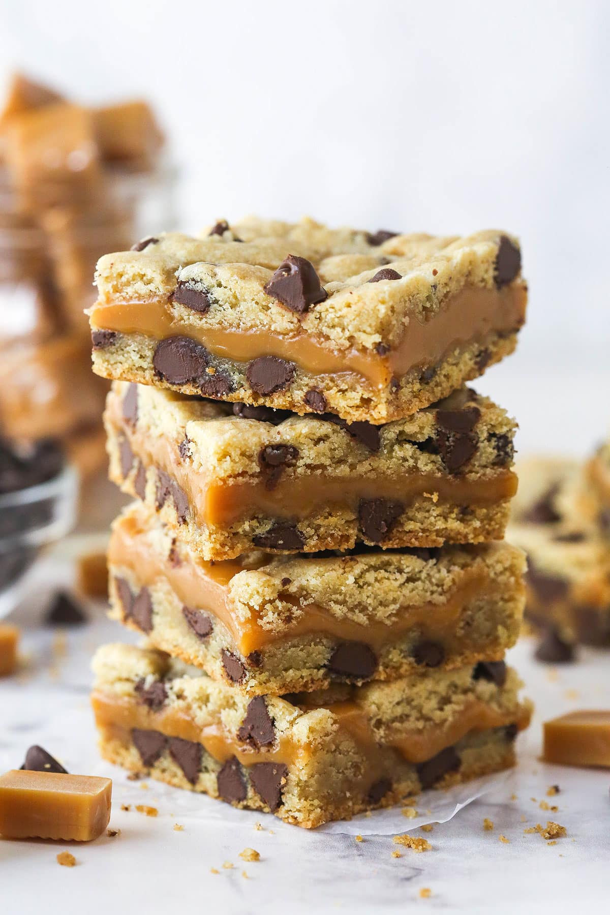 These Caramel Cookie Bars combine gooey caramel and chewy chocolate chip cookies in one perfect dessert. Easy to make! A stack of four caramel cookie bars