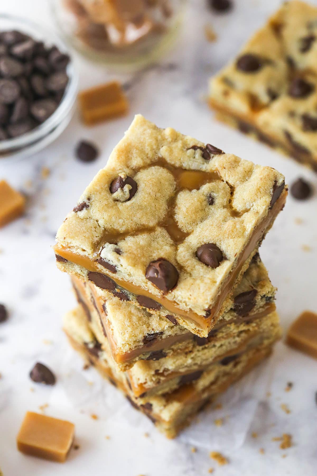 These Caramel Cookie Bars combine gooey caramel and chewy chocolate chip cookies in one perfect dessert. Easy to make! Overhead view of a stack of caramel cookie bars on the counter