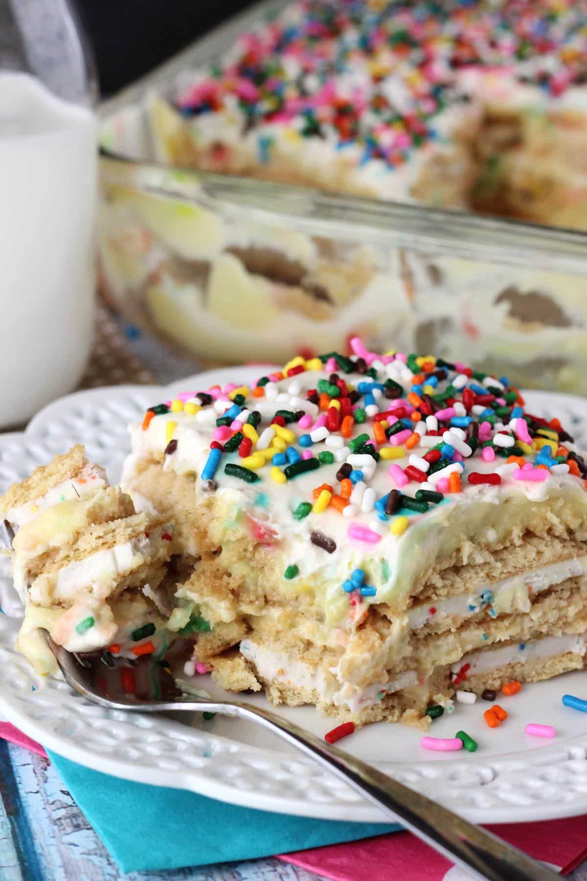 A slice of Funfetti birthday cake icebox cake with a bite removed on a fork on a small white plate.