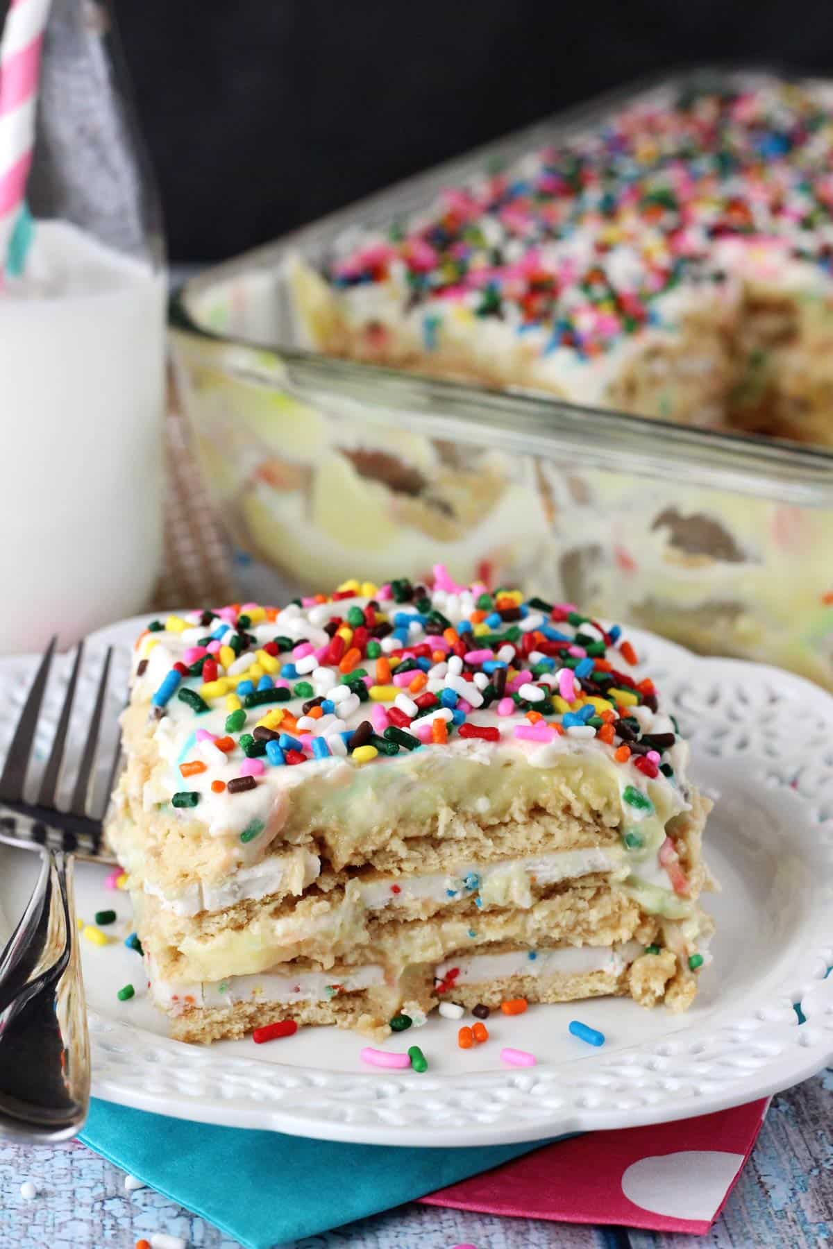 Close up of a slice of Funfetti birthday cake icebox cake with the rest of the cake in the backgroung.