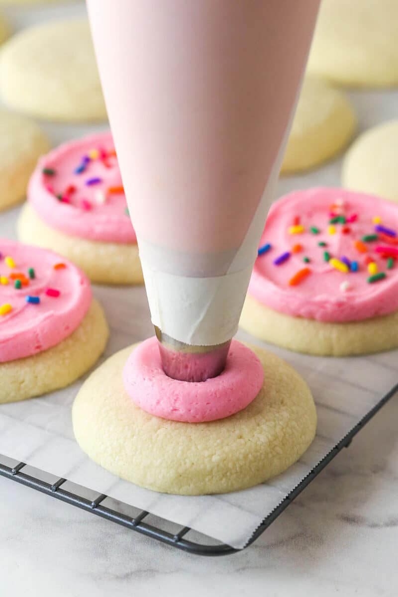 These copycat Lofthouse Cookies are soft and cakey with a melt-in-your-mouth texture and light flavor, just like the ones at the supermarket. Piping pink buttercream onto a cookie