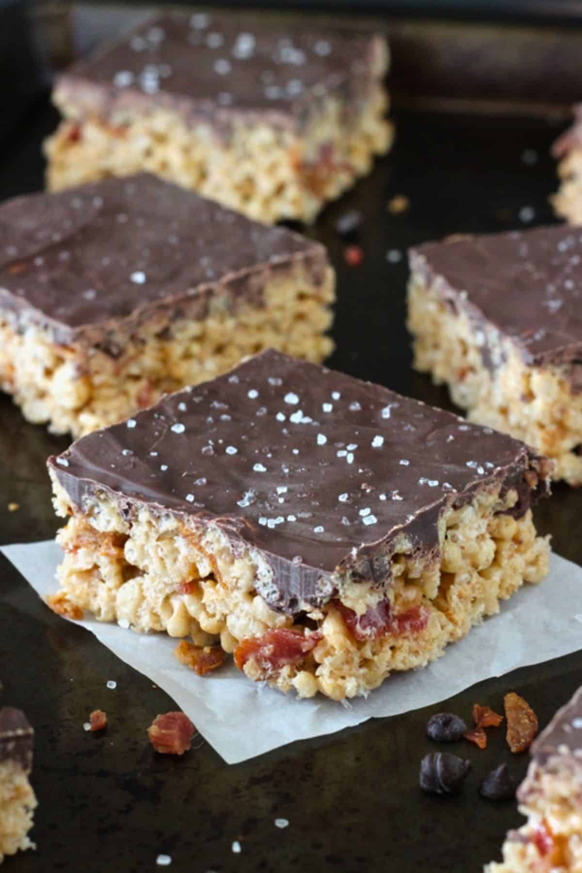 Close up of maple bacon rice krispie treats on a dark counter top.