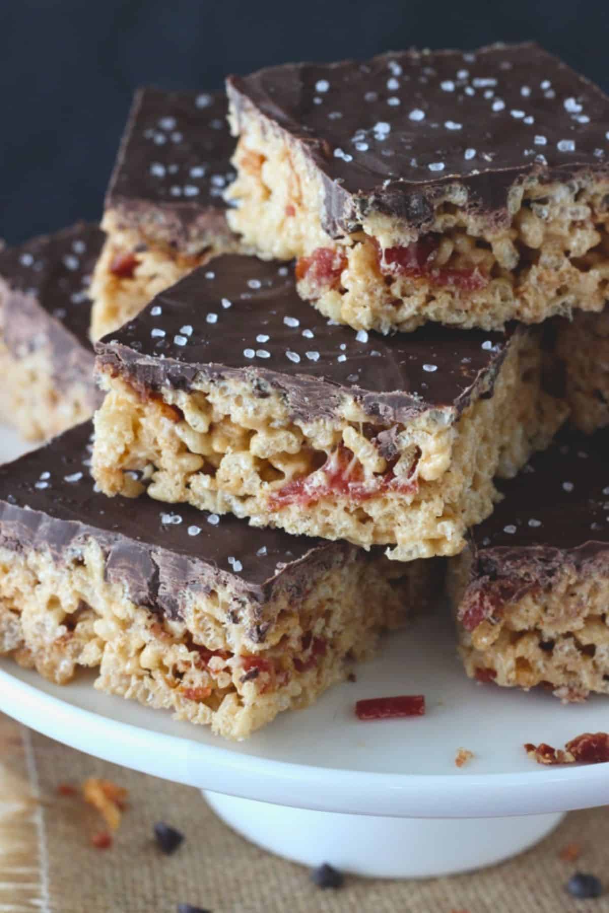 Close up of a several maple bacon rice krispie treats on a white cake stand.