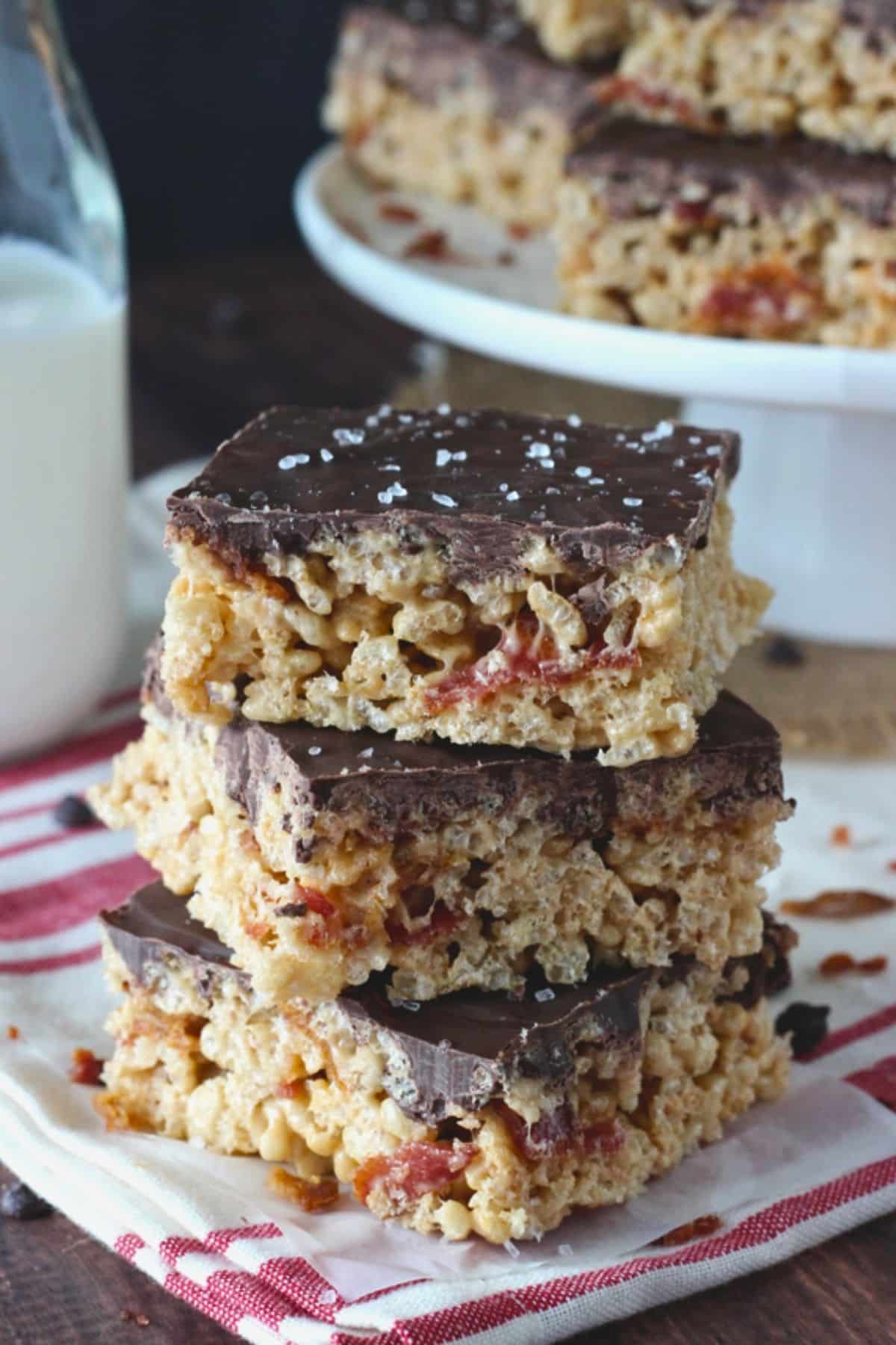 A stack of three maple bacon rice krispie treats with more treats in the background.