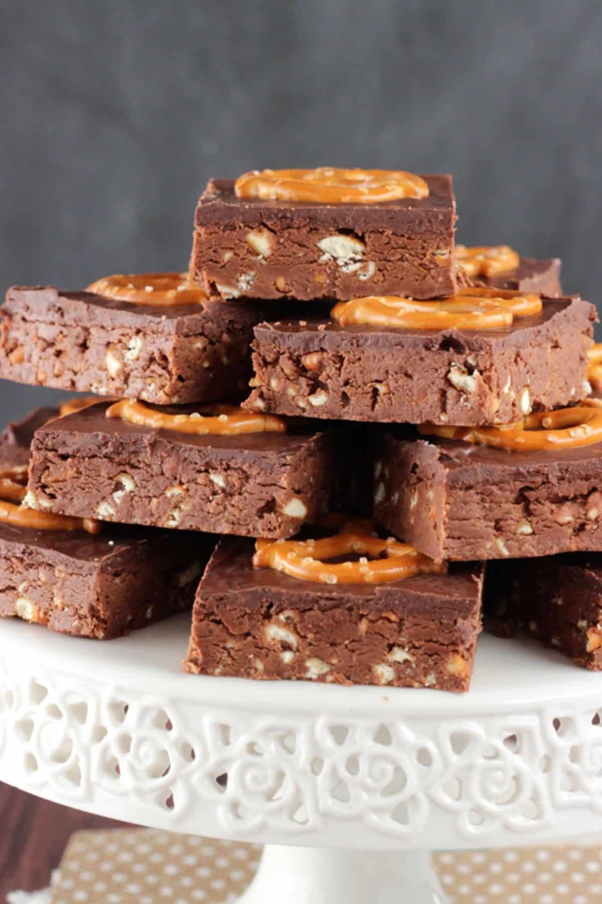 Side view of no bake Nutella pretzel bars piled on a white cake stand.