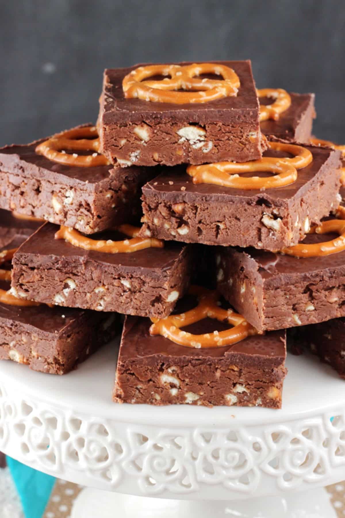A white cake stand piled with cut no bake Nutella pretzel bars.