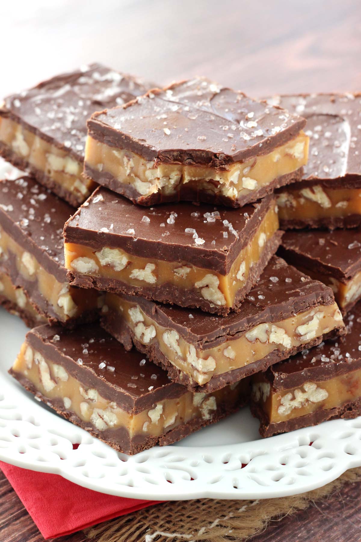 Pecan caramel turtle candy bars stacked on a white plate.