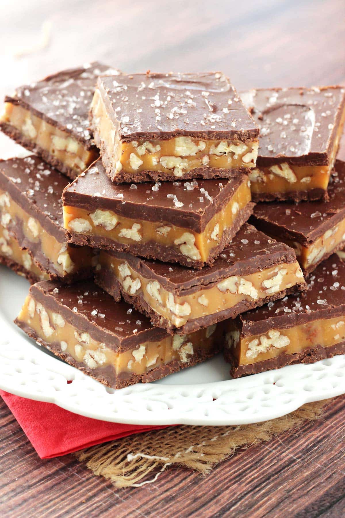 Close up of pecan caramel turtle candy bars stacked on a white plate.