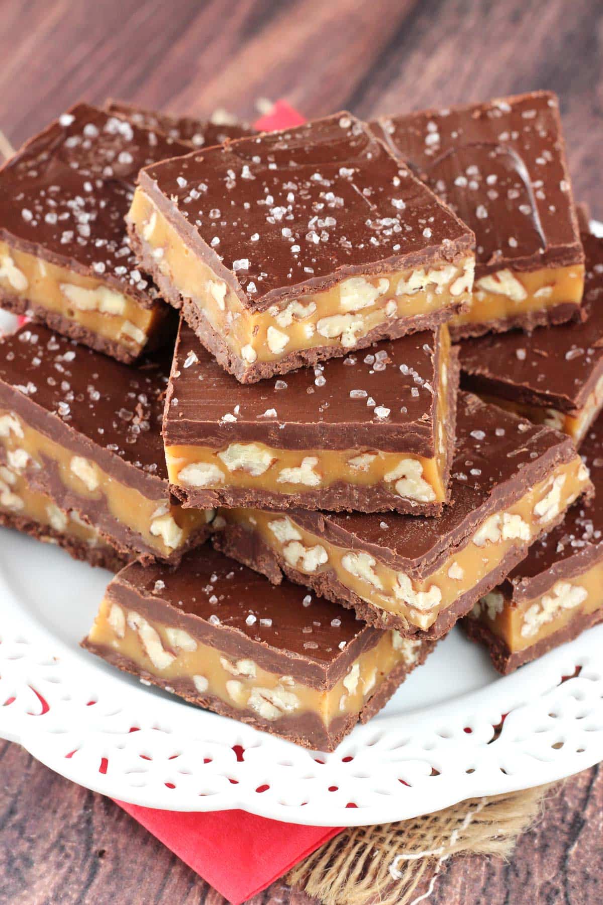 Close up of pecan caramel turtle candy bars stacked on a white plate.